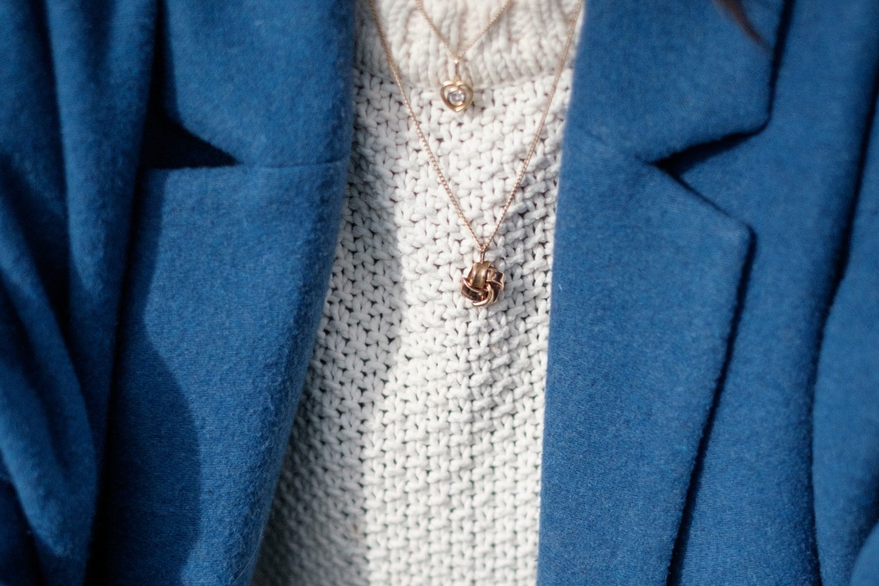 A close-up of a professionally dressed woman, wearing delicately layered necklaces.