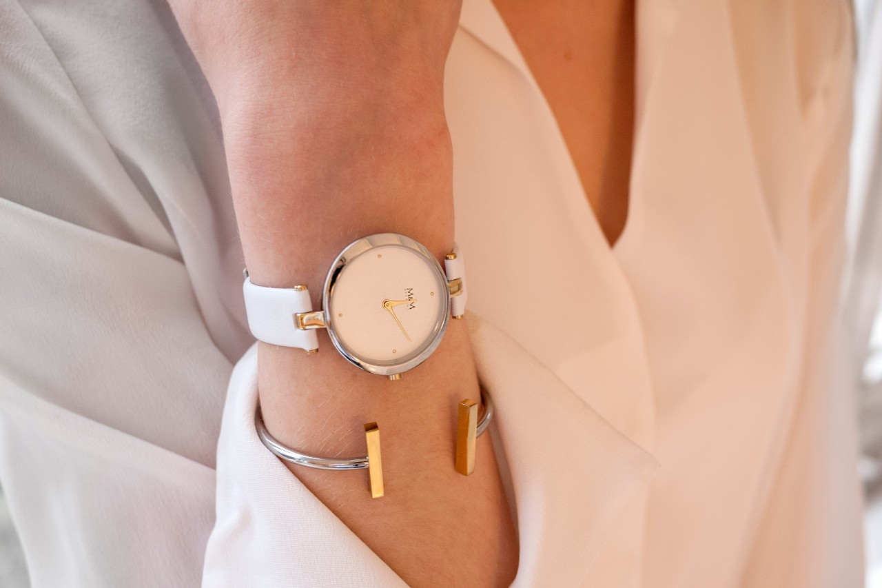 A close-up of a professionally dressed woman’s wrist, adorned with a minimalist wrist watch and bracelet.