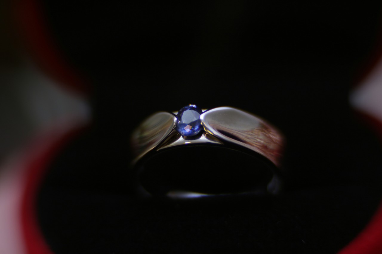 close up image of a white gold wedding band featuring a single round cut sapphire