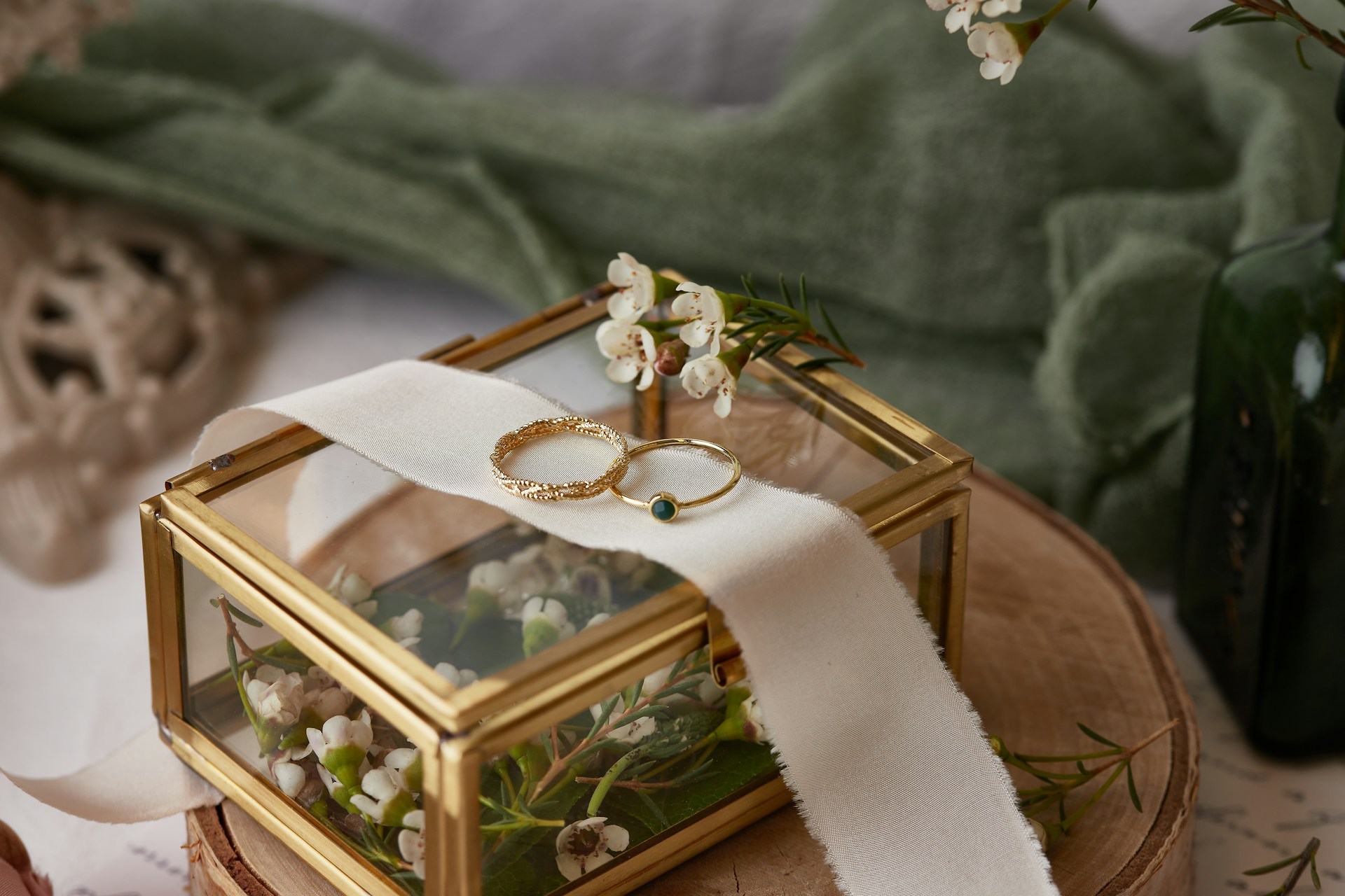 two unique wedding bands resting on a piece of cloth on a glass box