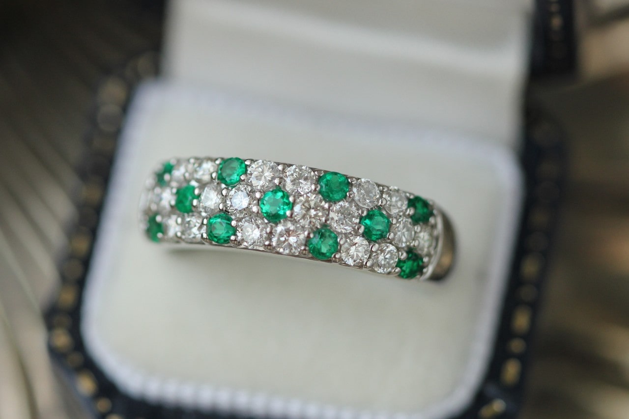 a wedding band decorated with emerald and diamonds