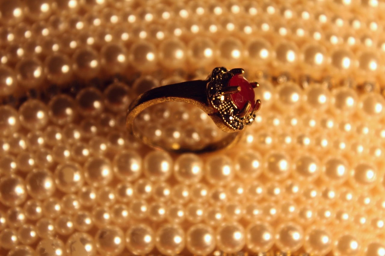 An elegant ruby ring nestled between glistening strings of pearls.