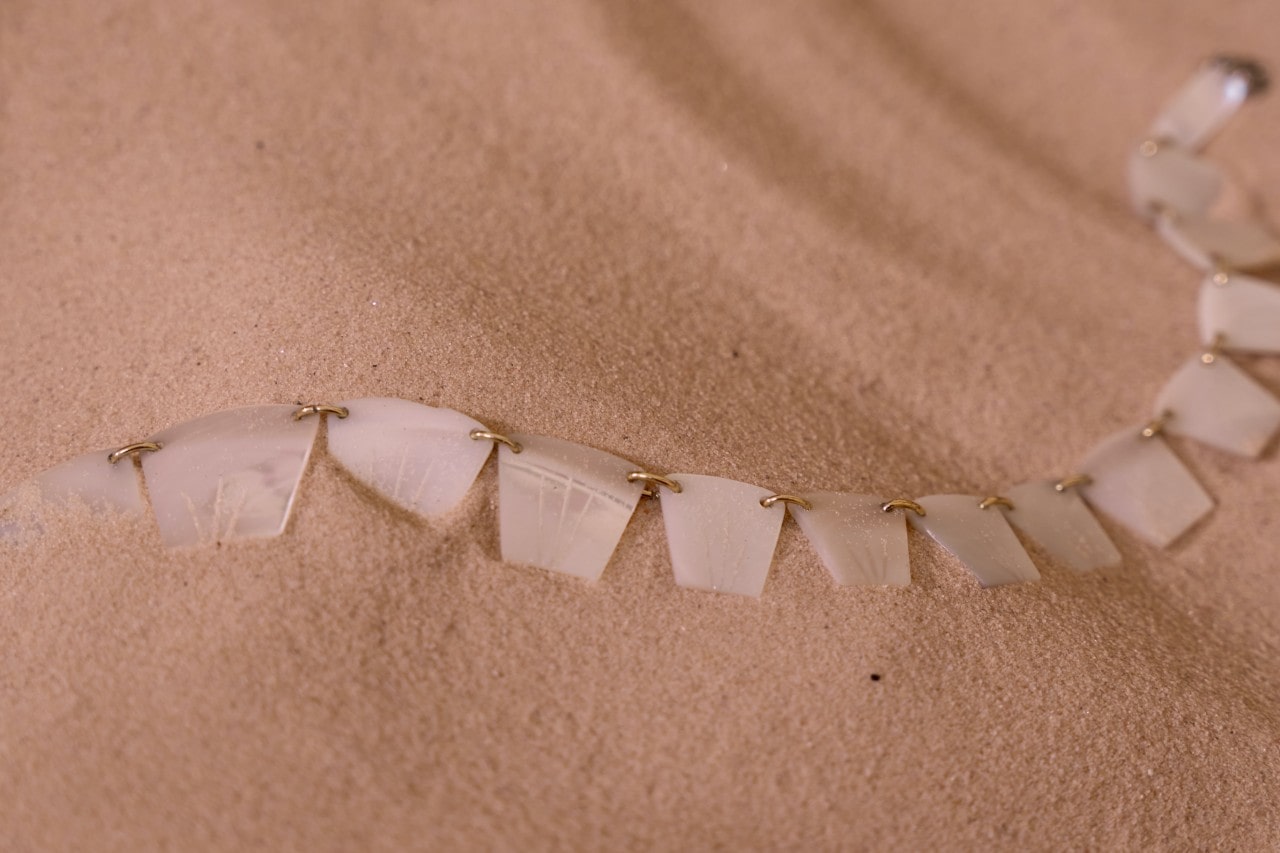 A beautiful necklace laying in soft beach sand.