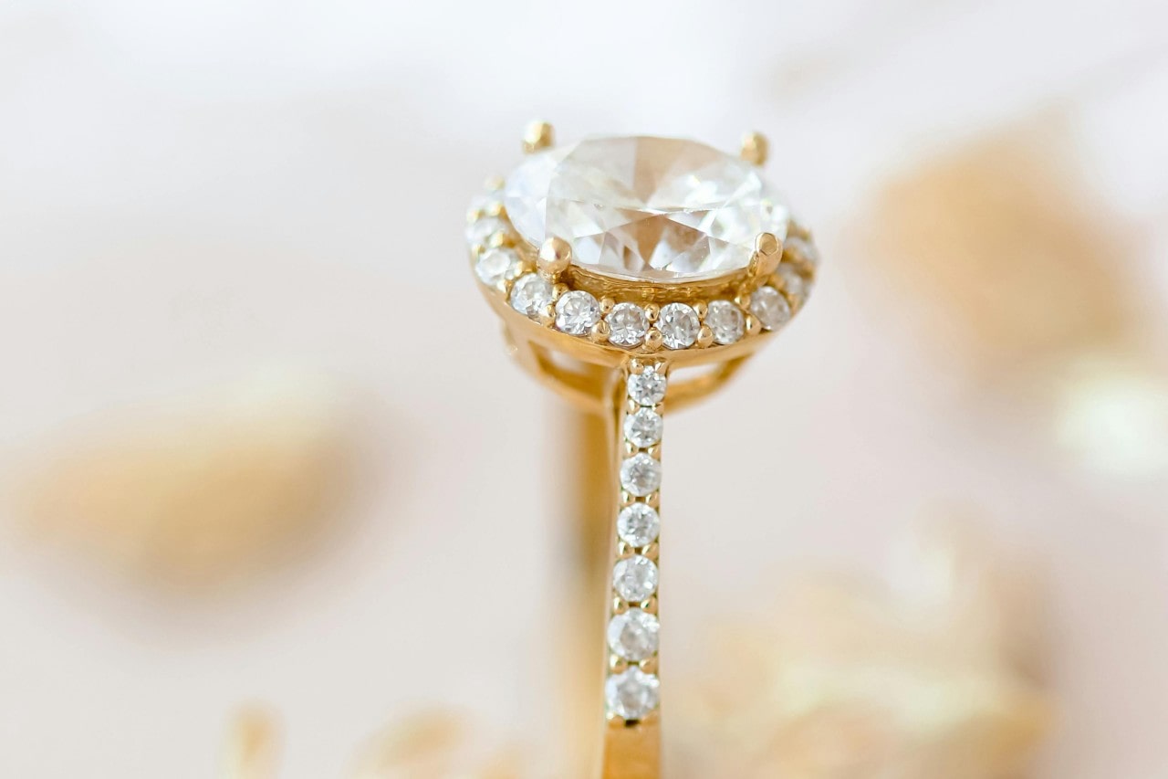 A closeup of a yellow gold halo engagement ring.