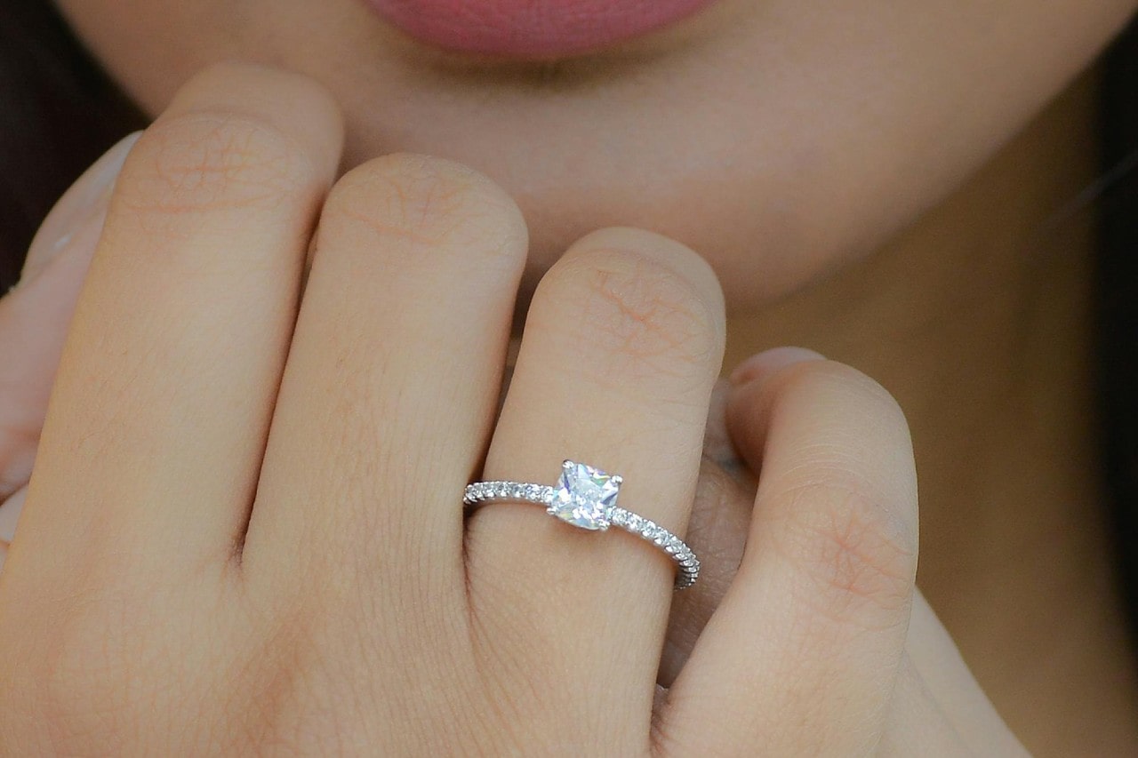 A woman wearing a side stone platinum engagement ring.