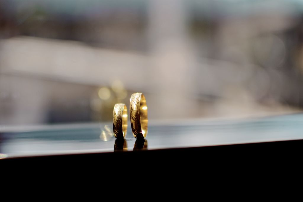 two matching yellow gold wedding bands sit on a windowsill.