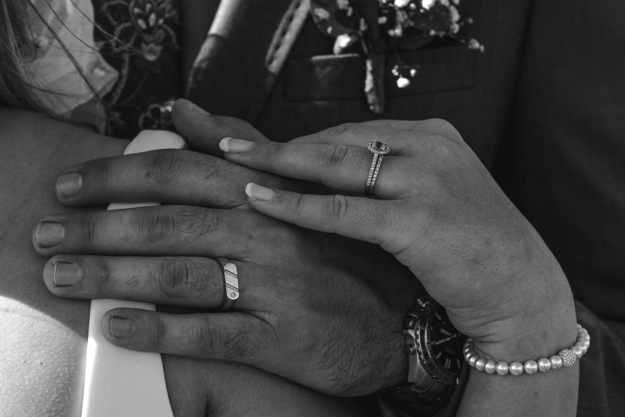 A married couple shares an intimate moment, wearing their rings.