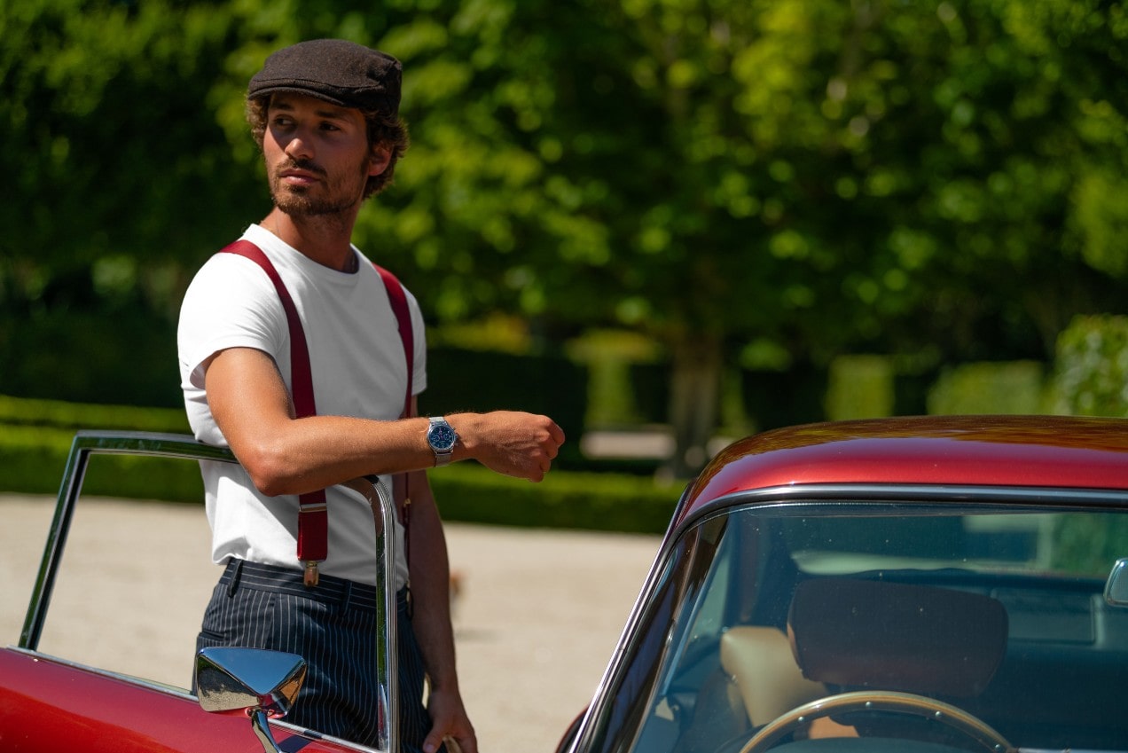 a man wearing a fine watch standing next to a red car