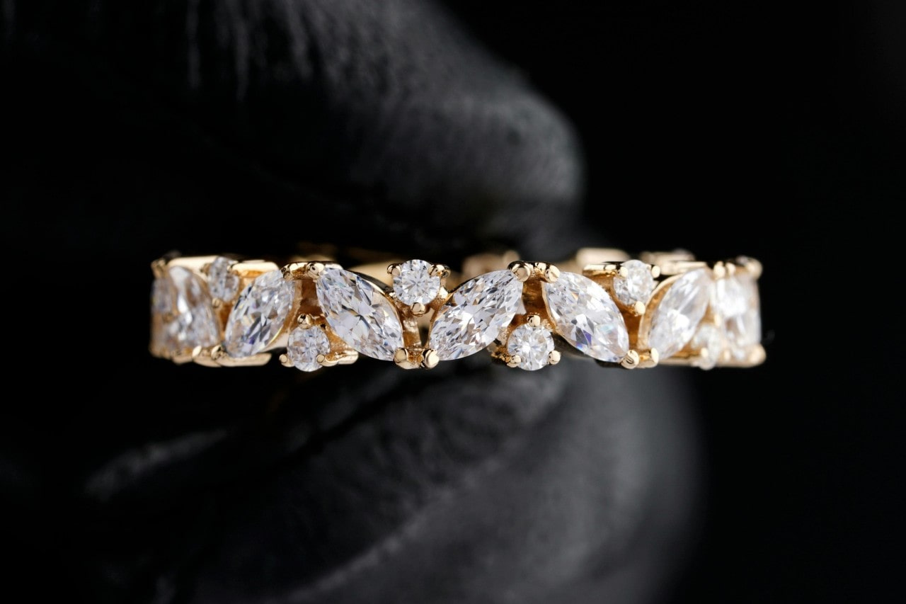 A close-up of a stunning band with round and marquise cut diamonds, displayed on a black backdrop.