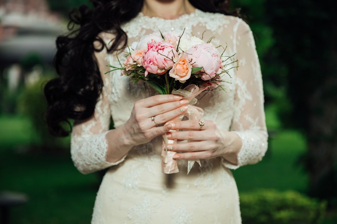 A bride holding a bouquet of flowers and wearing a vintage engagement ring.